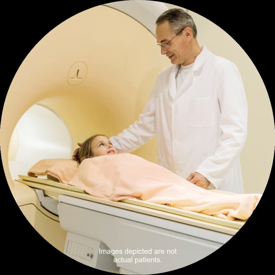 A healthcare provider with a young girl lying on her back about to enter an MRI machine.